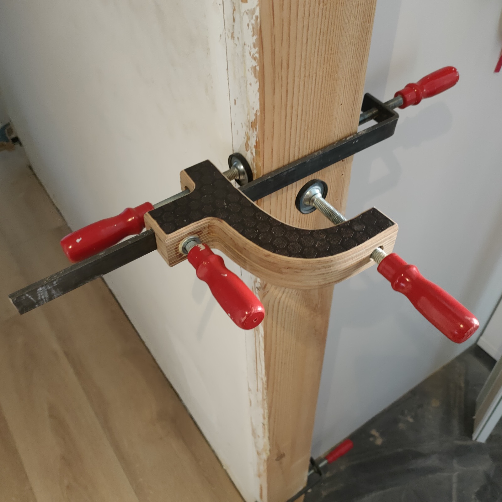 Catblock sujetando un premarco de madera durante el montaje de una puerta en obra